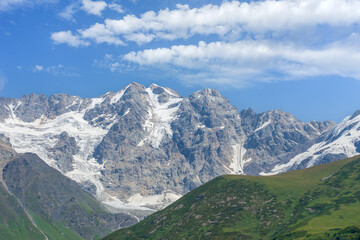 Shkhara Glacier towering over green valley in Georgia under blue sky