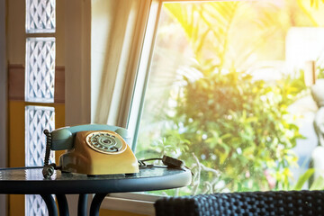 Classic rotary telephone or dial telephone stands on table by window in home. Old retro rotary dial...