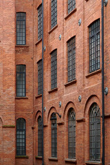 Obraz premium A close-up of an intricately designed brick building facade with arched windows, featuring metal outdoor stairs and black wrought iron lamps, showcasing the fusion of form and function in Łódź