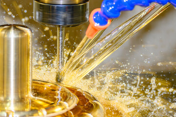 Close up scene the CNC milling machine finishing cut the brass shell mold parts with oil coolant...