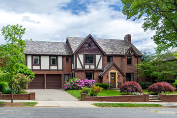 Elegant Tudor Revival family house with brick facade and blooming garden in Brookline, Massachusetts, USA 
