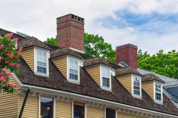 Fototapeta premium Hipped dormer windows and aged shingle roof gracing a traditional residential home exterior in Cambridge, Massachusetts, USA 