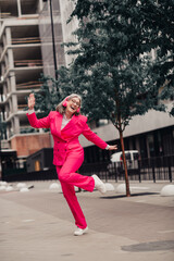 Confident stylish woman wearing pink suit enjoying a cheerful day outdoors in an urban cityscape