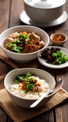 A bowl of aromatic, flavorful rice porridge sits alongside a hearty meat soup, both presented on a rustic wooden table.