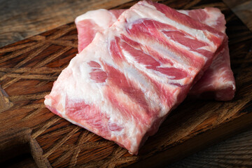 Raw pork ribs with spices, salt and rosemary on dark wooden background