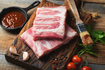 Raw pork ribs with spices, salt and rosemary on dark wooden background