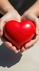 Obraz premium A person gently holding a red heart symbol.