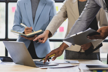 Businesspeople working together using laptop and documents in office meeting. Business team analyzing financial data using laptop and documents, discussing strategy during a productive office meeting.