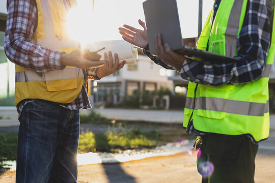 Contractors discussing building plans using laptop and blueprint.