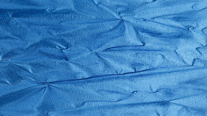 Blue foil texture with shiny metallic surface and wrinkled pattern, abstract luxury background for design and decoration.