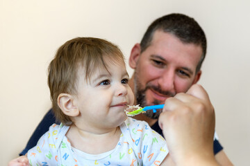 Father with male baby while being feed, authentic real scene of Latin American people