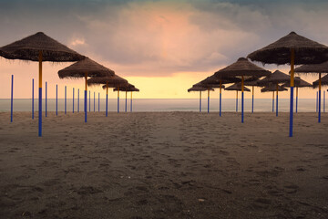 Sunset View of Empty Beach with Straw Parasols in Benalmadena Malaga Spain Mediterranean Coastline, vacation travel destination