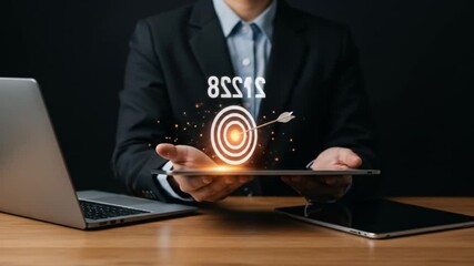 Man in suit holding target with arrow and the year 2028 above it with laptop and tablet on a desk - Powered by Adobe