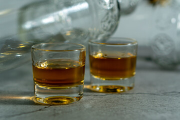 Two shot glasses of liquor are on a table next to a bottle