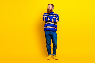 Fototapeta premium Casual man with beard in colorful attire standing confidently against a solid yellow background in a modern pose
