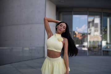 young woman in yello short dress walking on the street in the evening