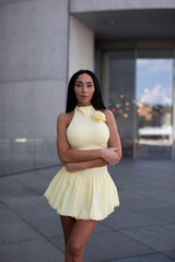 young woman in yello short dress walking on the street in the evening