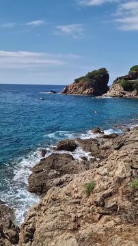 Sunny coastal view with sea waves gently crashing against the rocky shoreline. Beautiful turquoise water coastline of Cala sant Francesc Beach in Blanes (Costa Brava), Spain 