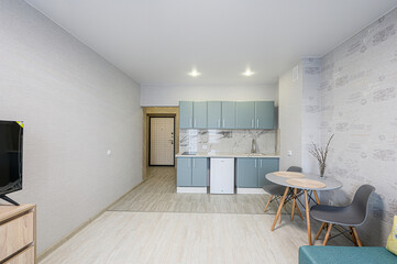 modern, compact apartment with light blue cabinets, a round table, and muted tones. Simple, clean design