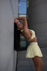 young woman in yello short dress walking on the street in the evening