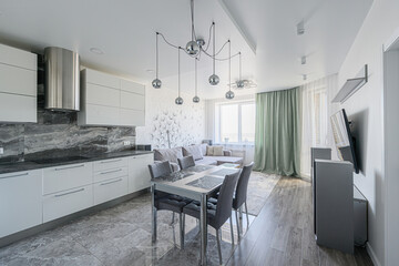 Modern kitchen and living space. Gray marble floors, white cabinets, gray dining set, and a dandelion feature wall