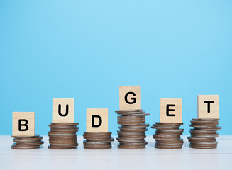 Wooden blocks with the word BUDGET on stack of coins. The concept about budget planning and allocation