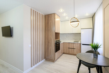 modern kitchen featuring wood-grain cabinets, a marble backsplash, a round dining table, and sleek pendant lighting