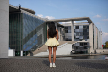 young woman in yello short dress walking on the street in the evening