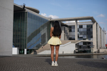 young woman in yello short dress walking on the street in the evening