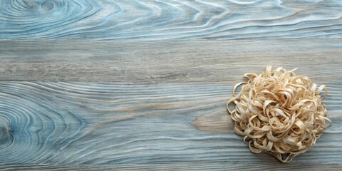 A pile of wood shavings rests on a pale blue and gray wooden surface