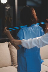 Doctor physiotherapist assisting a male patient while giving exercising treatment on stretching his...