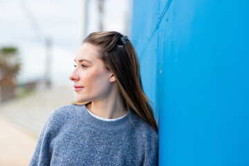 Thoughtful woman gazing sideways near blue wall