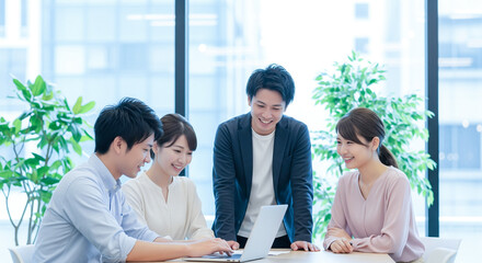 4人の日本人ビジネスパーソンがノートパソコンを使って行うオフィスでのチームディスカッション