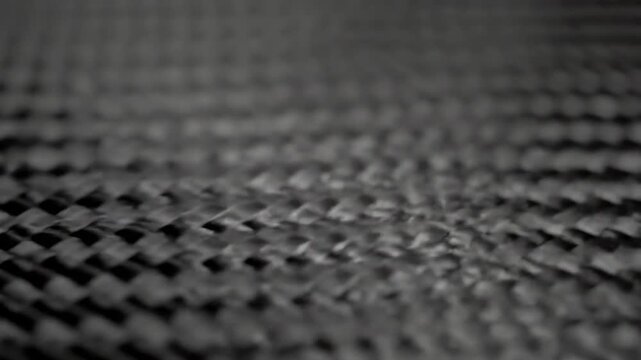 Detailed macro view of a woven black carbon fiber texture, a modern lightweight composite material creating a futuristic and abstract background