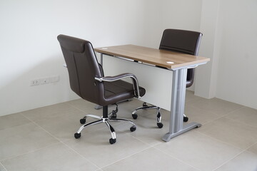Brown leather office chair sits in front of a wooden desk