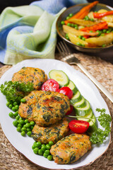 Chicken spinach burgers with green peas and vegetables on white plate