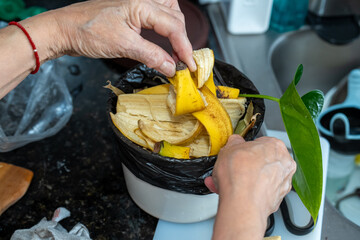 Hands Disposing Banana Peels into Organic Waste Bin in Kitchen