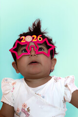 A girl thinks about her wishes for the new year 2026 while wearing shiny glasses from the year 2026. Concept: children's New Year's dreams.