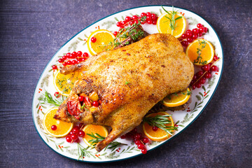 Roasted whole duck with fuits and berries served on oval side dish plate. High angle view