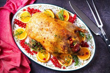 Roasted whole duck with fuits and berries served on oval side dish plate. High angle view