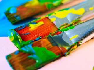 Fototapeta premium Closeup of Paintbrushes with Colorful Paint Splatters on White Surface Art Supplies.