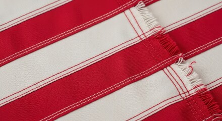 Close-up of red and white striped fabric with detailed stitching and frayed edges, showcasing textile texture and pattern.