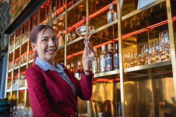 Asian bartendy mixologist holding cocktail glass in bar