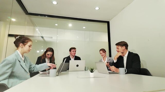 Team Meeting in Progress: Colleagues engaged in a collaborative discussion around a conference table, utilizing laptops and engaging in active listening.