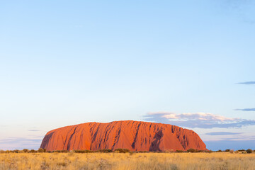 Uluru or Ayers rock with yellow grass at sunset in spring within Uluru Kata Tjuta National Park, Australia. Uluru or Ayers Rock is a large sandstone monolith near the centre of Australia.  © JHVEPhoto