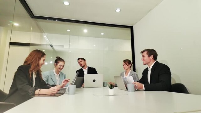 Teamwork in Modern Office: A diverse group of colleagues engages in a collaborative meeting in a bright, modern office space.
