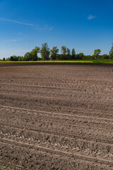 A rural landscape with a plowed empty field at the beginning of spring