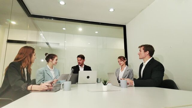 Boardroom Discussion: A diverse group of business professionals engages in a productive meeting around a conference table, illuminated by modern office lighting.