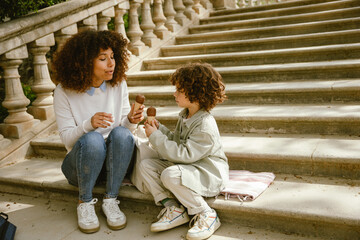 Mother and son sit on the stairs and hold ice cream