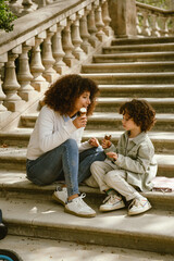 Mother and son eating ice cream while sitting on a blanket on the stairs